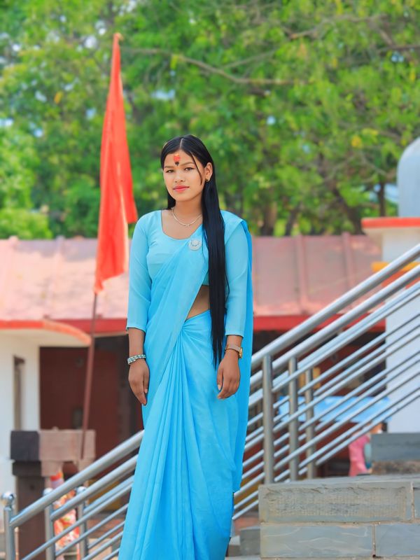 A young woman in a traditional blue saree outside a haveli