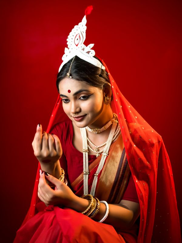 Woman in a red saree turning back under a chandelier